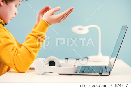 Child boy with headphones studying at home with laptop Child boy with headphones studying at home with laptop 73674537