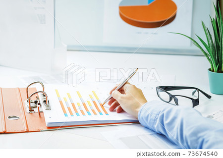 Finance. Female hand with calculator on financial graphs on desk Finance. Female hand with calculator on financial graphs on desk 73674540