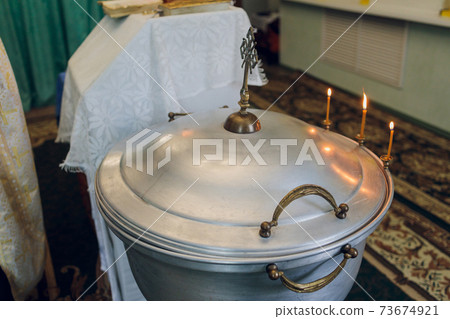 Water is poured into the font for bathing the baby in the church, religious traditions. 73674921