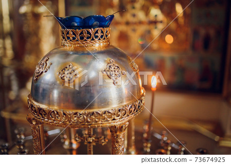 Lighting candles in a catholic temple . Candles are lit near the altar in a Catholic temple. 73674925