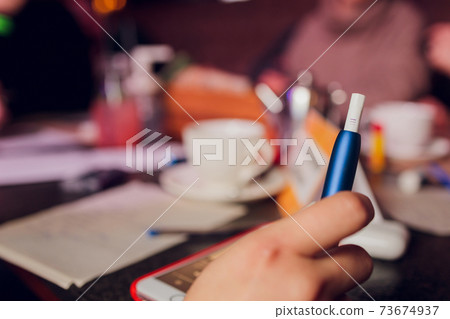 heat-not-burn tobacco product technology. Woman holding e-cigarette in his hand before smoking. 73674937