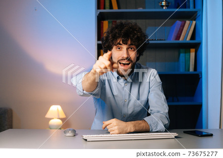 Front view of cheerful young businessman talking on video call and pointing finger to display screen Front view of cheerful young businessman talking on video call and pointing finger to display screen 73675277