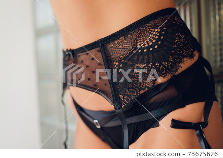 Cropped photo of an attractive young woman s hips wearing in black lingerie with stockings, laces. Sideways. Erotic ladies fashion concept. Stock photo 73675626