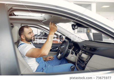 Handsome man in a blue uniform checks the car 73675977