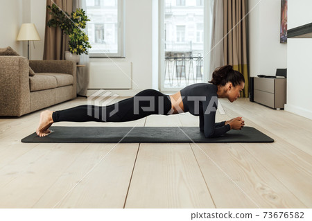 Side view of a slim woman in sportswear doing plank Side view of a slim woman in sportswear doing plank 73676582