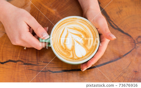 latte art on wooden table. Cup of coffee with heart shape. 73676916