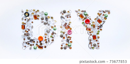 Diy lettering collected from handmade tools such as buttons, ear wires, locks, sequins, pendants on a white background. Craft and hobby concept. Banner format. Diy lettering collected from handmade tools such as buttons, ear wires, locks, sequins, pendants on a white background. Craft and hobby concept. Banner format. 73677853