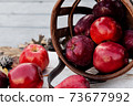 Harvest of red apples in a basket in autumn season, fresh organic fruits on wooden background 73677992