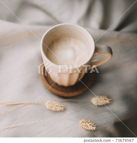 Cup of coffee with milk on beige plaid. Flat lay, top view still life morning breakfast. Comfort, cosiness and warmth concept. Photo in light pastel colors 73679567