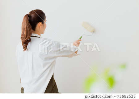 Woman painting the wall 73682523