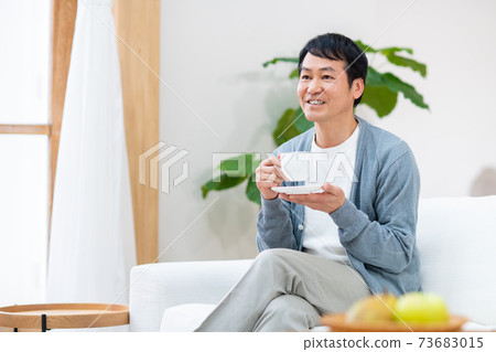 Middle man drinking coffee in the living room Middle man drinking coffee in the living room 73683015