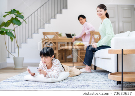 在客廳中使用智能手機的孩子和父母看著 在客廳中使用智能手機的孩子和父母看著 73683637