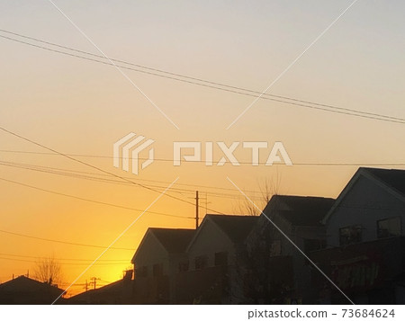 Silhouette scenery of the cityscape where the pale orange sky at sunset and the electric wires are connected 73684624