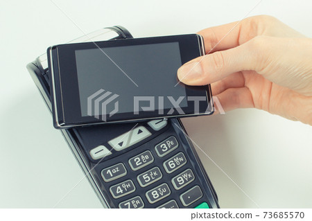 Hand using payment terminal and mobile phone with NFC technology 73685570
