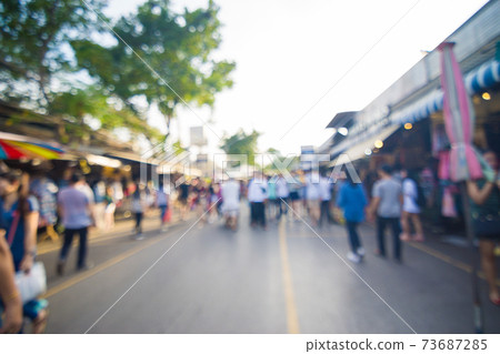 Blurred crowd of anonymous people walking on outdoor street 73687285