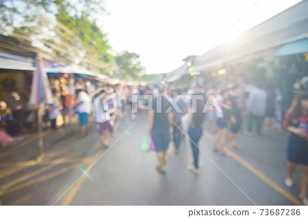 Blurred crowd of anonymous people walking on outdoor street 73687286