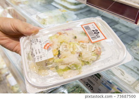 A female shopper picking up a side dish with a discount sticker on hand 73687500