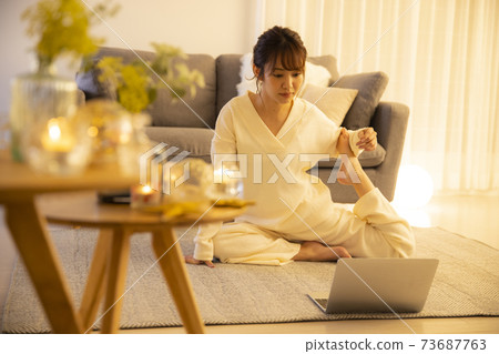 Woman doing yoga in the living room at night 73687763