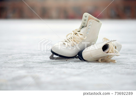 A pair of White Figure Skates are standing on an open ice rink. Winter sport 73692289