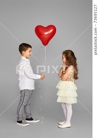 couple of little girl and boy with red heart balloons 73695127