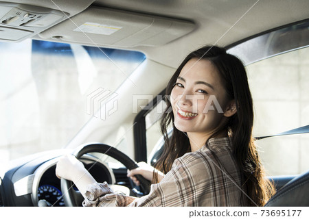 A young woman driving a car 73695177