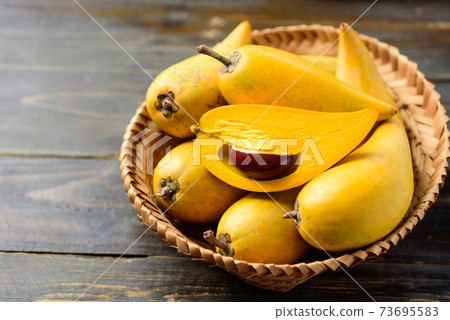 Eggfruit or canistel in a basket on wooden table 73695583