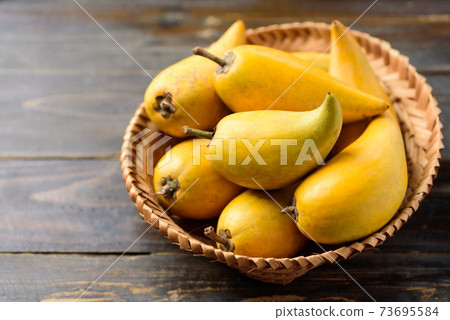 Eggfruit or canistel in a basket on wooden table Eggfruit or canistel in a basket on wooden table 73695584