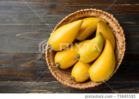 Eggfruit or canistel in a basket on wooden table, Top view 73695585