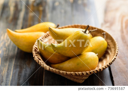 Eggfruit or canistel in a basket on wooden table 73695587