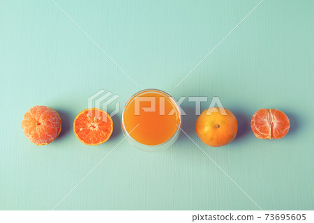 Fresh tangerine orange fruit and juice in glass on vintage color background 73695605