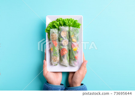 Fresh vegetables spring roll on plate holding by hand Fresh vegetables spring roll on plate holding by hand 73695644