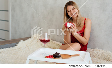 Valentines Day concept. Festive breakfast. The blonde holds a gift Valentines Day concept. Festive breakfast. The blonde holds a gift 73699438
