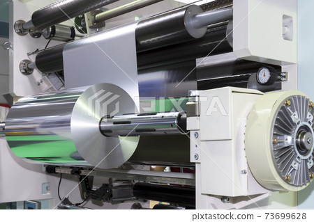 roll of aluminum foil for food packaging on automatic packing machine in food product factory. industrial and technology concept. 73699628