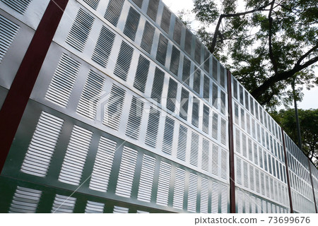 SELANGOR, MALAYSIA - JULY 2, 2020: Noise barriers are installed along the vehicle lane bordering the residence to prevent noise pollution to the locals. 73699676