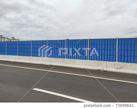 SELANGOR, MALAYSIA - JULY 2, 2020: Noise barriers are installed along the vehicle lane bordering the residence to prevent noise pollution to the locals. 73699681