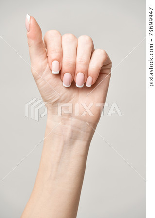 Beautiful Female Hands with French manicure over light grey background 73699947