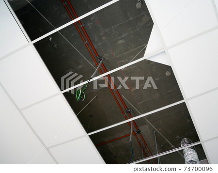 KUALA LUMPUR, MALAYSIA -JULY 24 2020: The suspended ceiling, electrical wiring, cabling and mechanical equipment under installation. It is hanging at the floor soffit. Cover by ceiling board. KUALA LUMPUR, MALAYSIA -JULY 24 2020: The suspended ceiling, electrical wiring, cabling and mechanical equipment under installation. It is hanging at the floor soffit. Cover by ceiling board. 73700096
