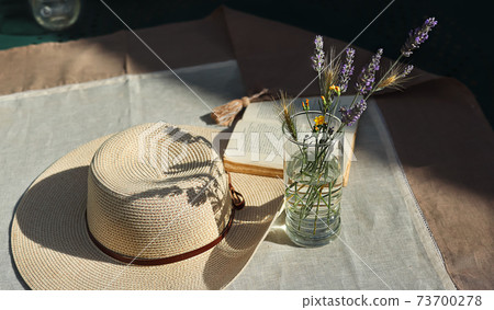 Wildflowers and a hat on a table Wildflowers and a hat on a table 73700278