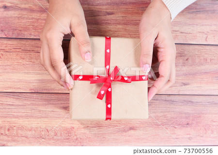 top view of women hand holding a gift box on table top view of women hand holding a gift box on table 73700556