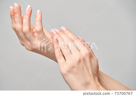Beautiful Female Hands with French manicure over light grey background 73700767