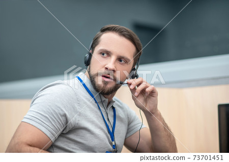Man with headphones listening and speaking into microphone Man with headphones listening and speaking into microphone 73701451