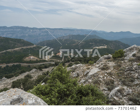 view of Supramonte Mountains with white limestone rock, green trees and Passo di Genna Silana in the valley. Sardinia, Italy. Summer cloudy day view of Supramonte Mountains with white limestone rock, green trees and Passo di Genna Silana in the valley. Sardinia, Italy. Summer cloudy day 73701462