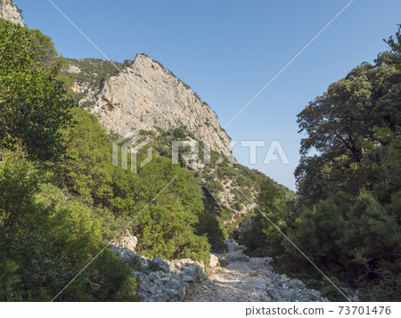A view of rocky hiking path to Cala Goloritze beach, limestone rocks. Famous travel destination. Gulf of Orosei, Sardinia, Italy, September A view of rocky hiking path to Cala Goloritze beach, limestone rocks. Famous travel destination. Gulf of Orosei, Sardinia, Italy, September 73701476