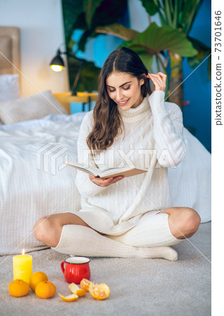 Young beautiful woman siting on the floor and reading a book 73701646