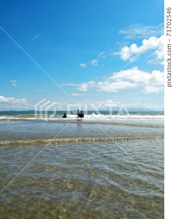 MERSING, MALAYSIA - JANUARY 12, 2020: Tropical beach during the day. Children and adults are having fun bathing on the tropical beach. The seawater is crystal clear and no pollution. MERSING, MALAYSIA - JANUARY 12, 2020: Tropical beach during the day. Children and adults are having fun bathing on the tropical beach. The seawater is crystal clear and no pollution. 73702546