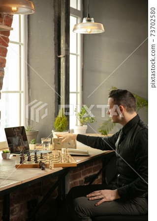 Serious Caucasian man chess player playing chess online with his student. 73702580