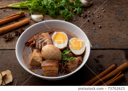 hard-boiled eggs in the sweet gravy sauce in white bowl. 73702625