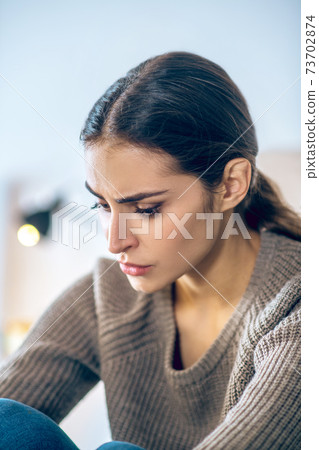 Dark-haired young woman looking stressed and unhappy Dark-haired young woman looking stressed and unhappy 73702874