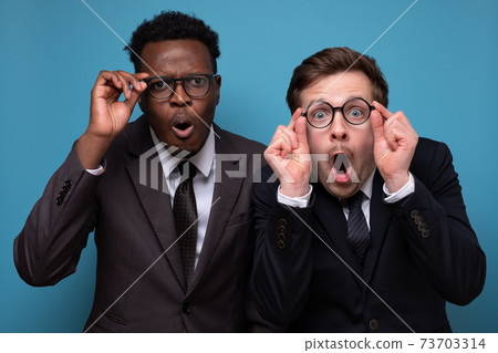 Two excited men looking at you wearing glasses being shocked. Two excited men looking at you wearing glasses being shocked. 73703314
