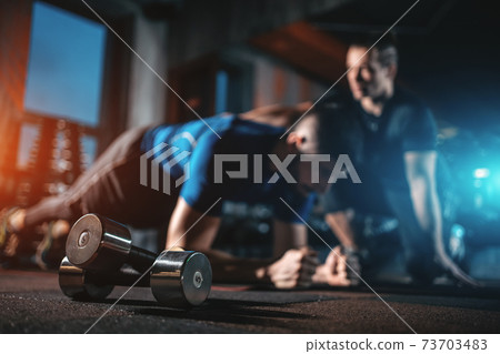 young man has workout with personal trainer in modern gym young man has workout with personal trainer in modern gym 73703483